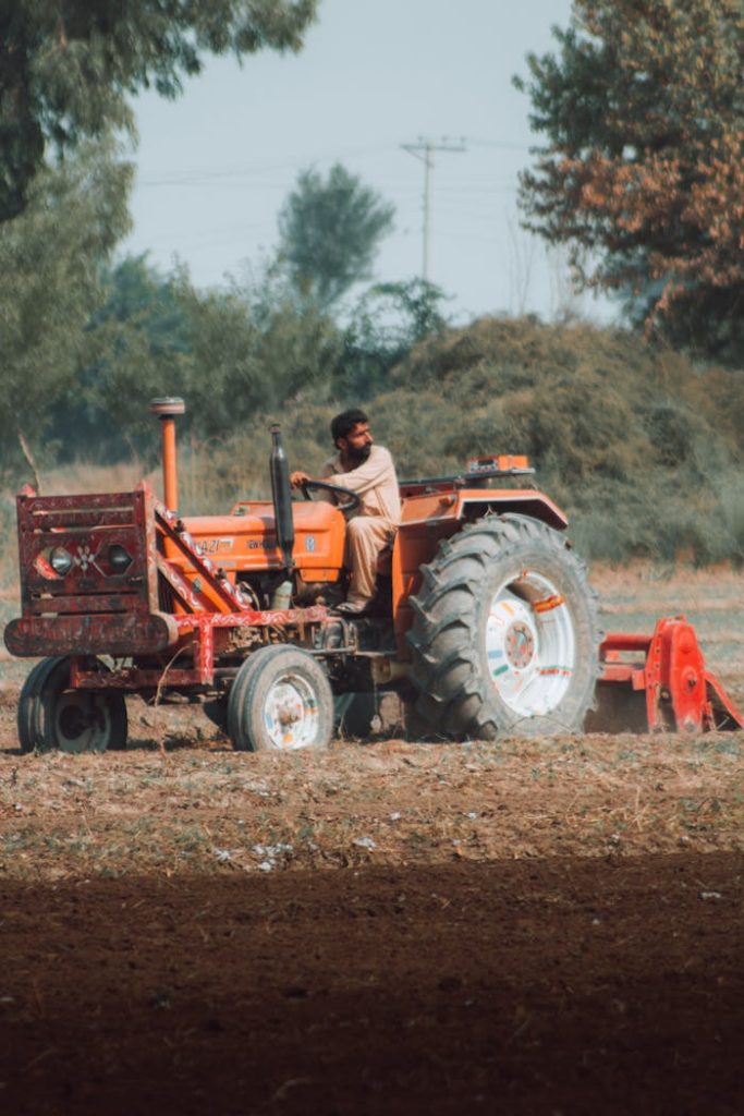 A farmer driving a tractor in a rural field, embodying traditional agriculture.