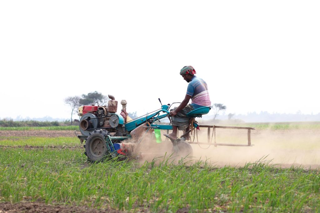 A farmer uses a tractor to plow a field in Pabna, showcasing rural agriculture.