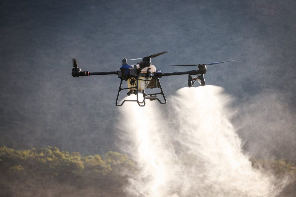 A drone dispersing spray over a green field, showcasing modern agricultural technology and crop management.